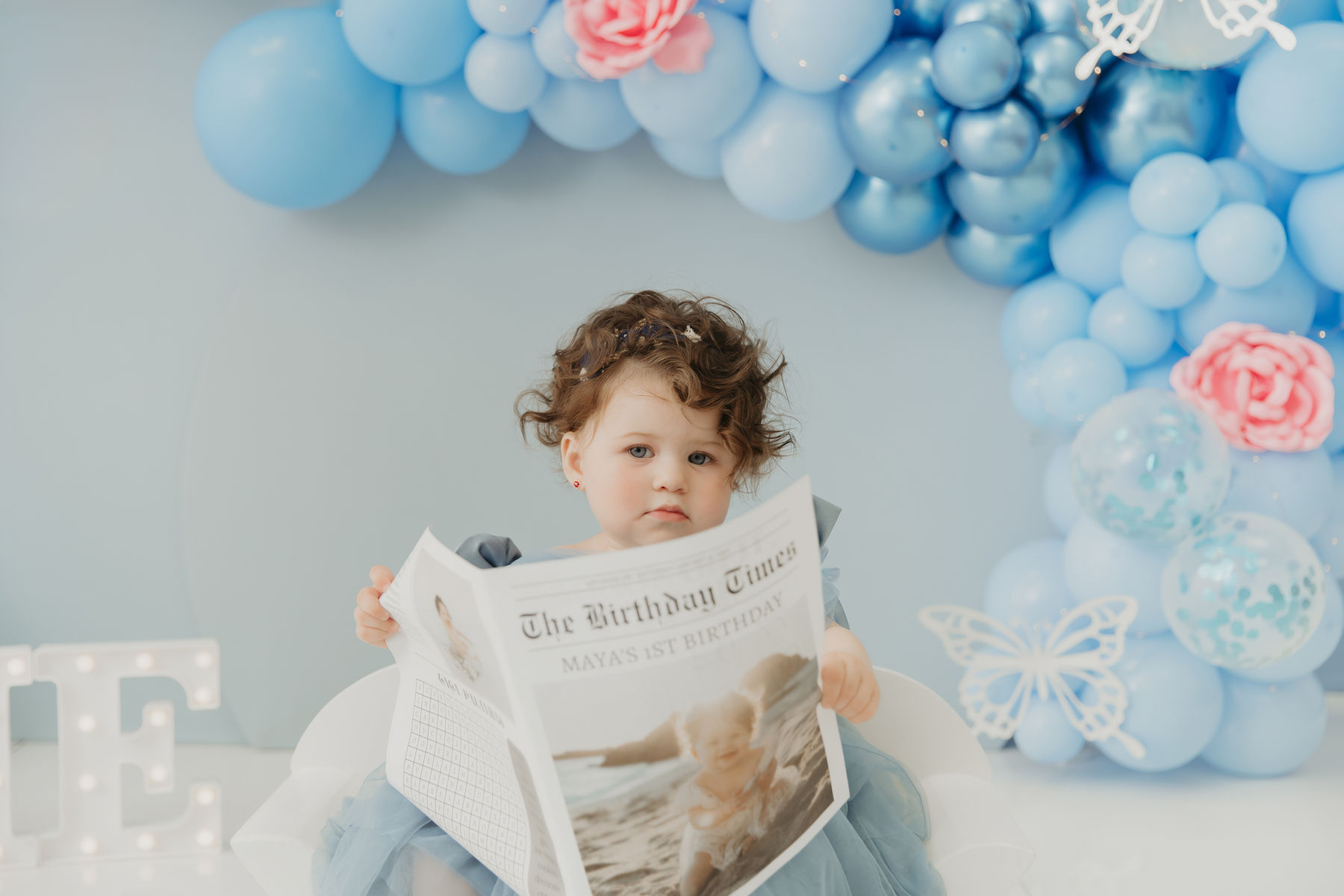 First birthday cake smash session with a soft blue balloon arch